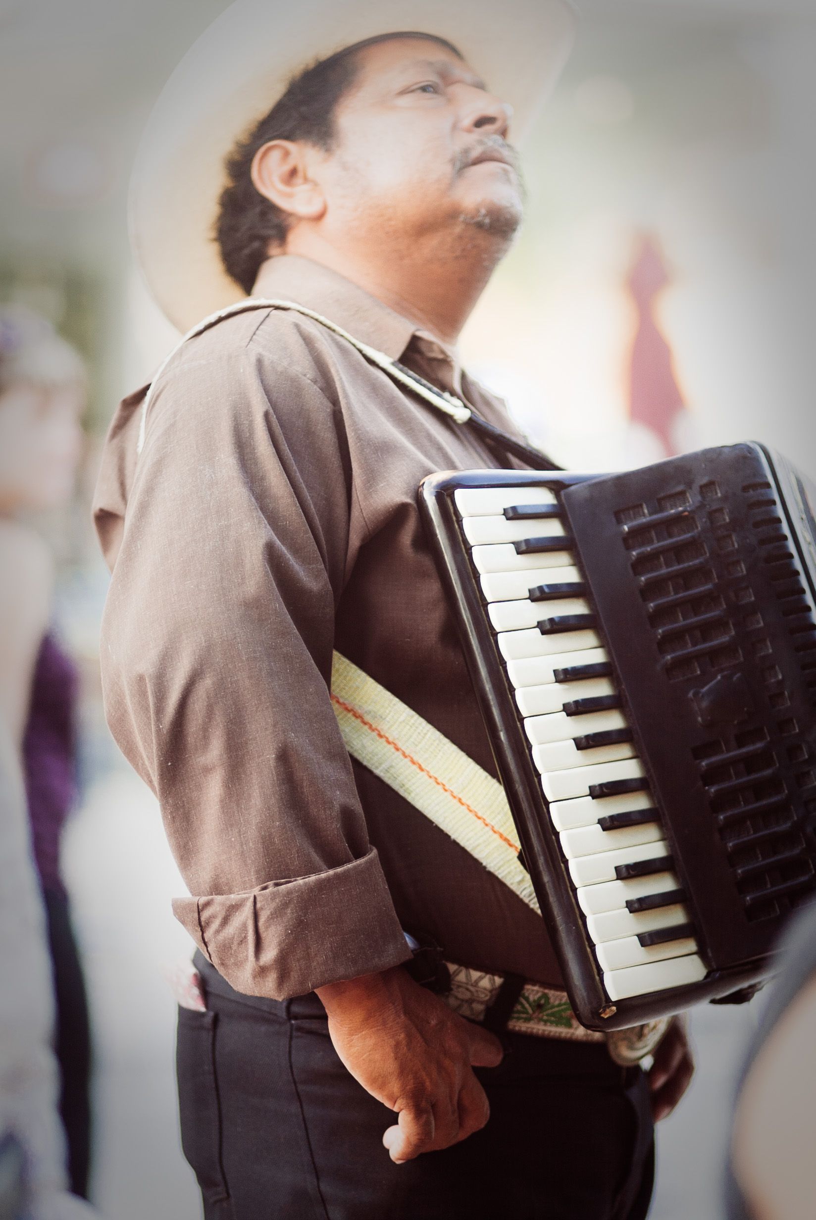 A man with a hat plays an accordion outdoors, showcasing musical culture.