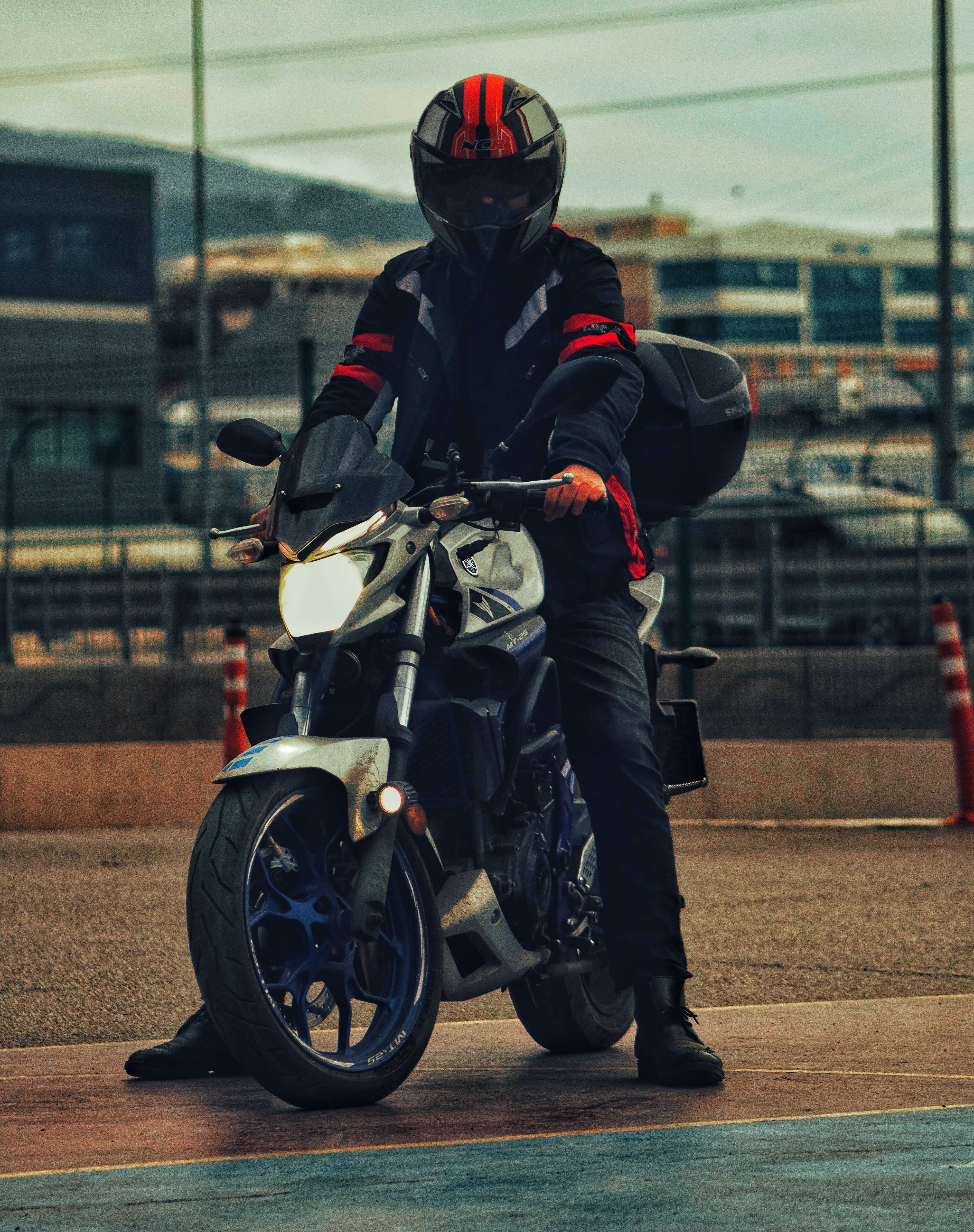 Adult motorcyclist in protective gear riding a sleek motorcycle on a city street during daytime.