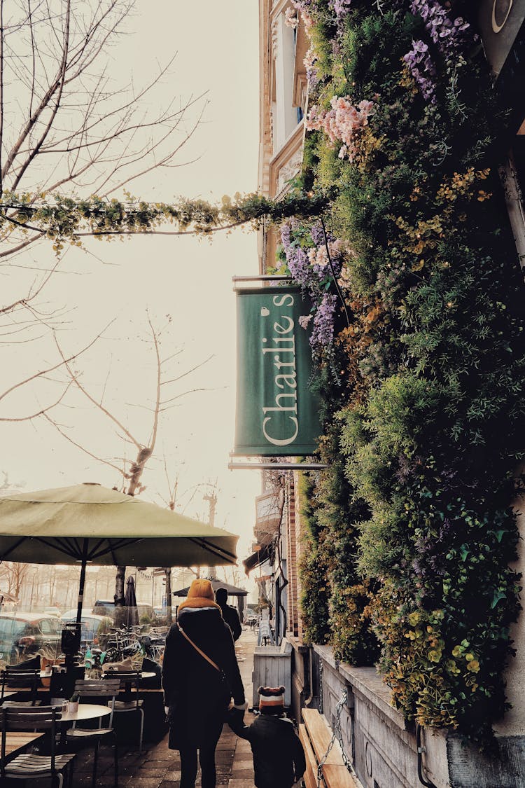 Woman With Kid Walking By Restaurant