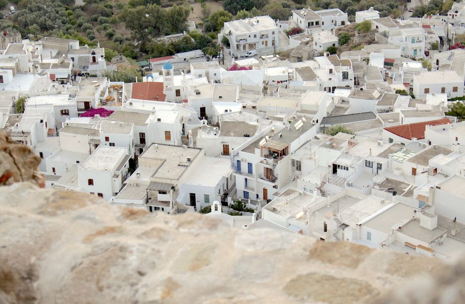Panoramic view of whitewashed buildings in a traditional Greek village, capturing the charm and warmth.