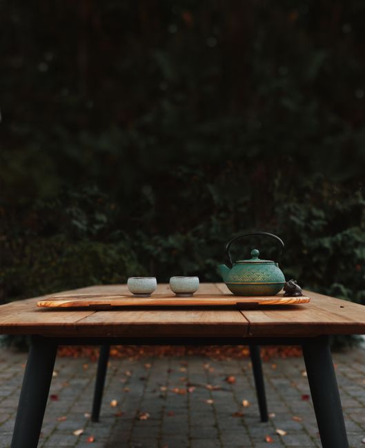 Elegant tea set on a wooden table captures simplicity and tranquility in an autumn garden.