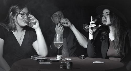 Free Group of adults enjoying drinks and cigars during a poker night. Stock Photo