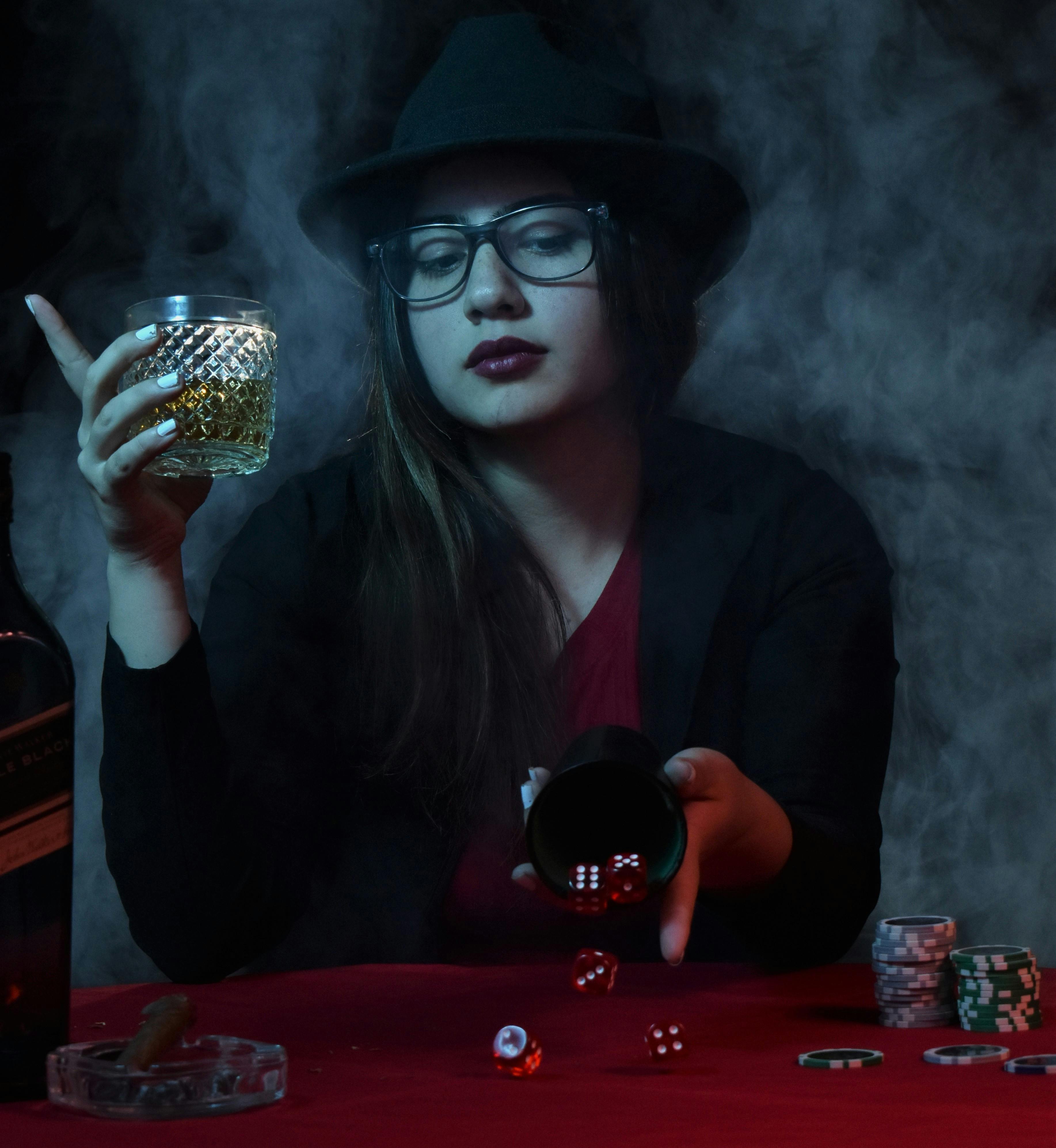 Woman Throwing Dice on a Table and Holding a Drink · Free Stock Photo