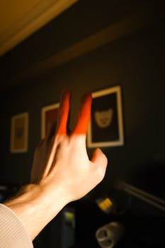 A human hand reaching towards framed artwork, highlighted by warm sunlight.