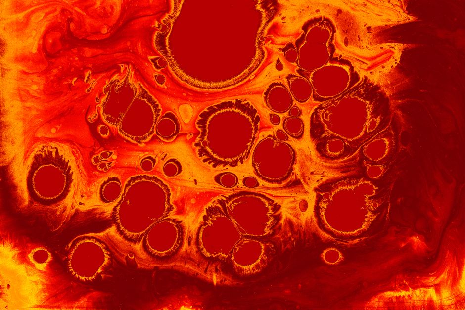 Colorful abstract fluid art with vibrant red and yellow swirls resembling cells or organic forms.