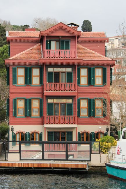 A charming Ottoman-style building on Istanbul's waterfront, featuring vibrant balconies and windows.