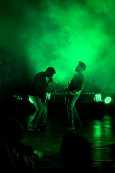 Energetic rock band performance under vibrant green lights in Osmangazi, Bursa.