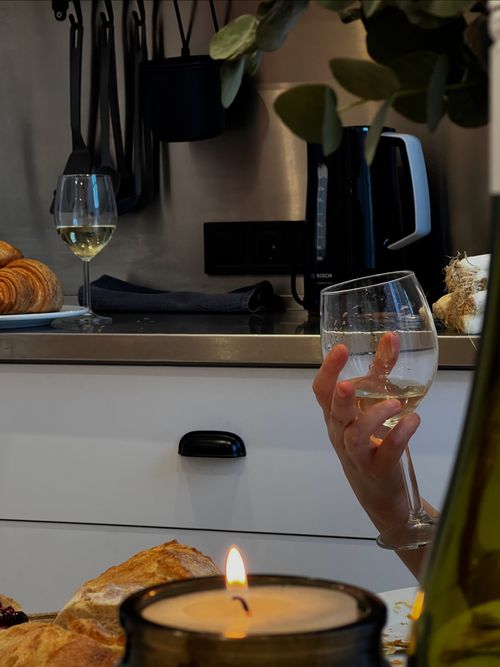 Free A warm, inviting kitchen setup with a glass of white wine and a lighted candle. Stock Photo