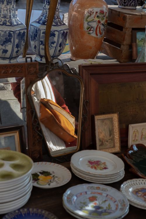 Free Antique market stall featuring vintage plates, porcelain vases, and a decorative mirror reflection. Stock Photo