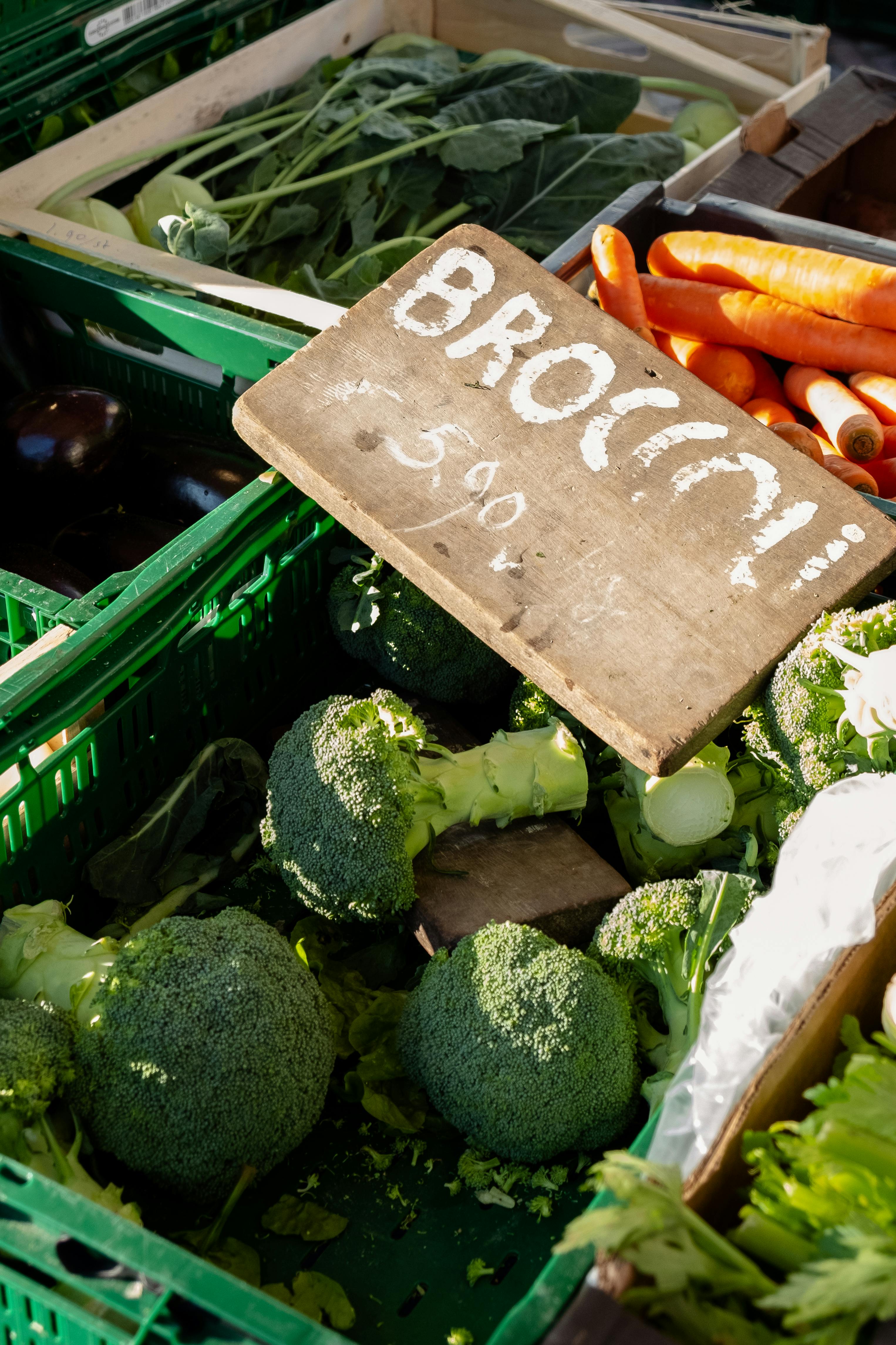 Colorful assortment of fresh vegetables including broccoli and carrots at an outdoor market.