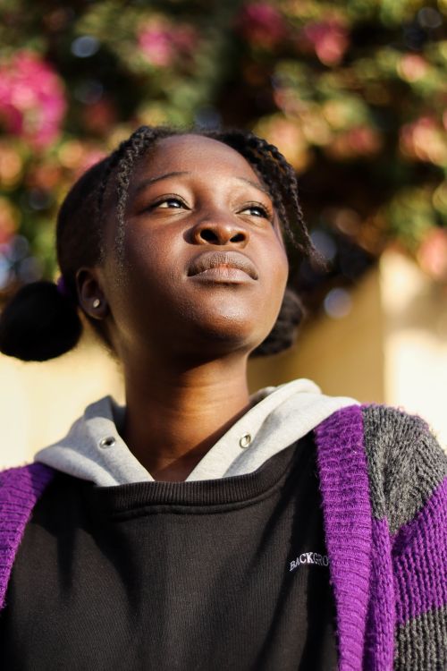 Free Fashionable teenager in knitted cardigan and hoodie looking ahead outdoors. Stock Photo