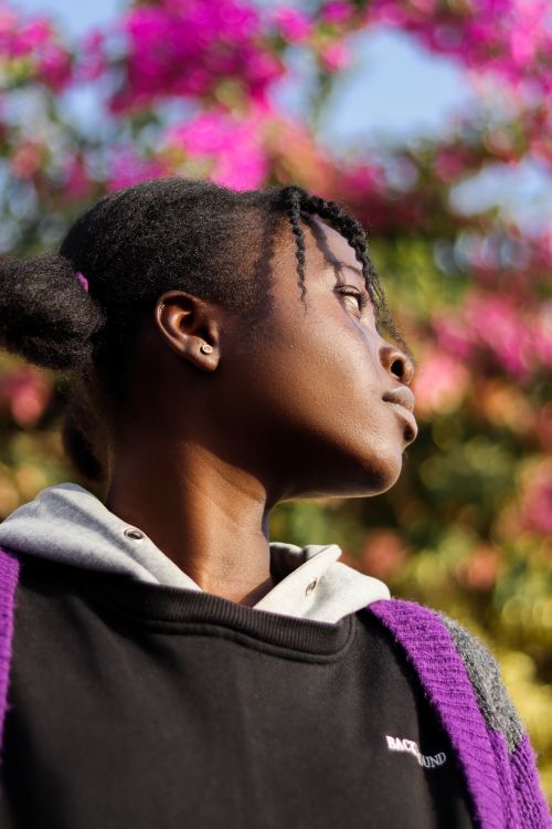 Free A captivating portrait of a woman outdoors against a vibrant, floral background. Stock Photo