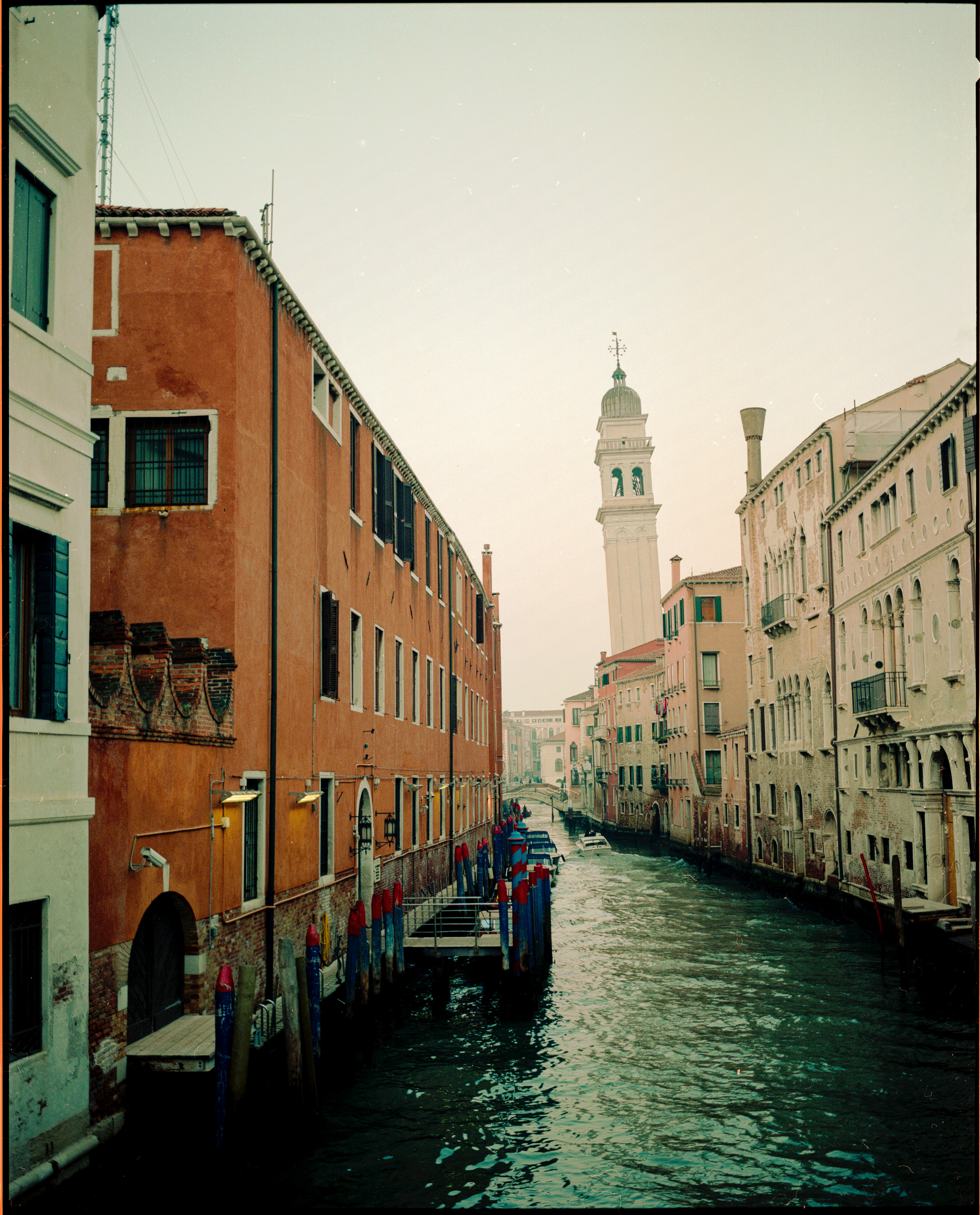 Tranquil Venetian canal with historic buildings and a prominent tower.