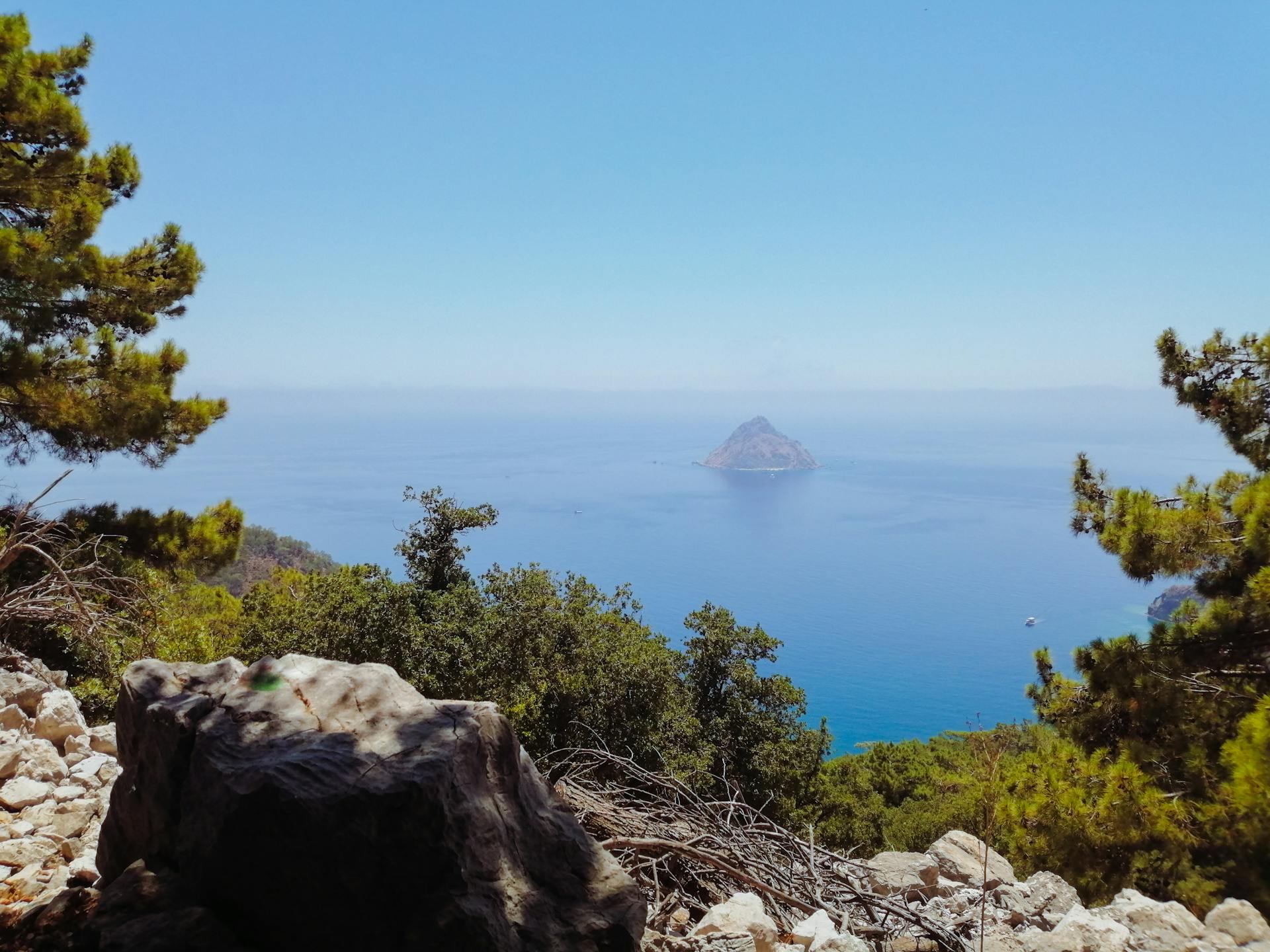 Peaceful view of the Mediterranean Sea and island from Antalya cliffs with lush greenery.
