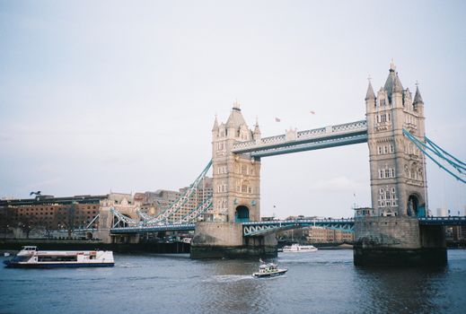 Beautiful overview of London's iconic Tower Bridge with boats sailing on the Thames River.