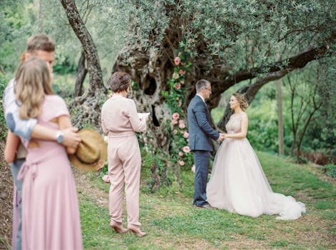Romantic outdoor wedding ceremony with bride and groom under a flowering tree.