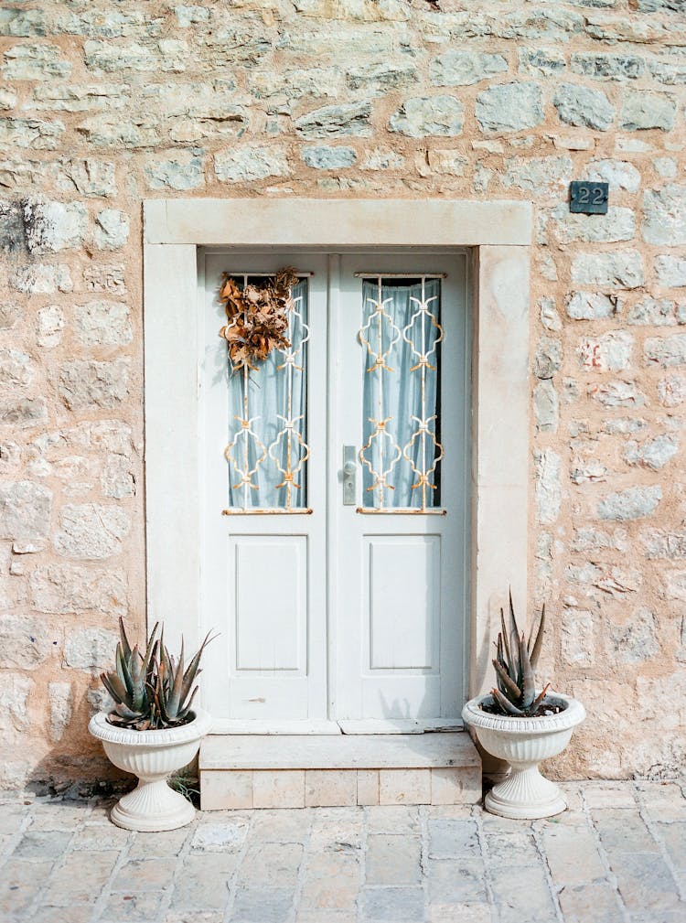 White Wooden Doors And Plants At Old House Facade