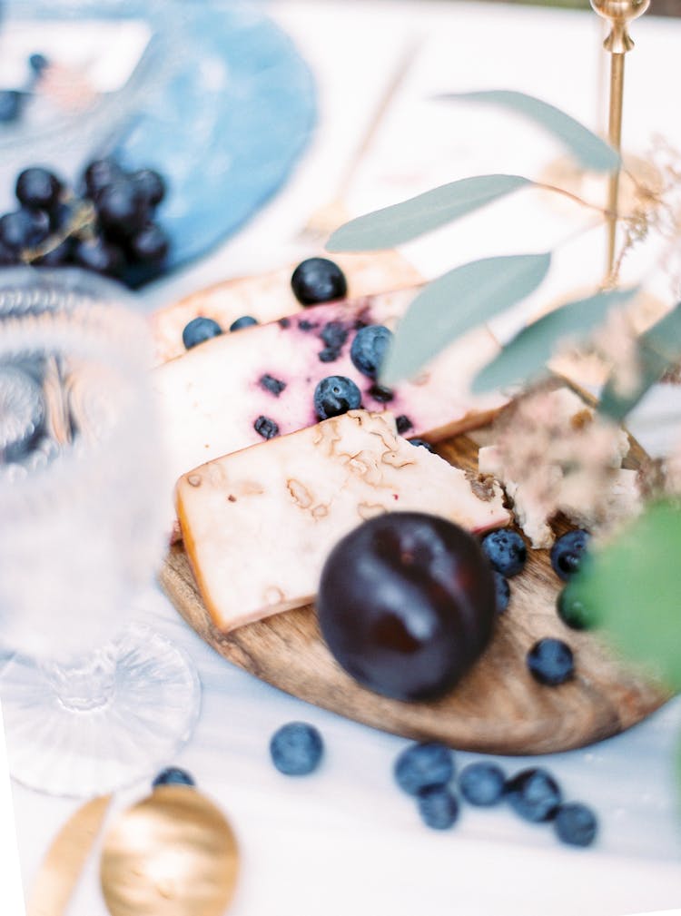 Cheese And Fruits On Board On Table