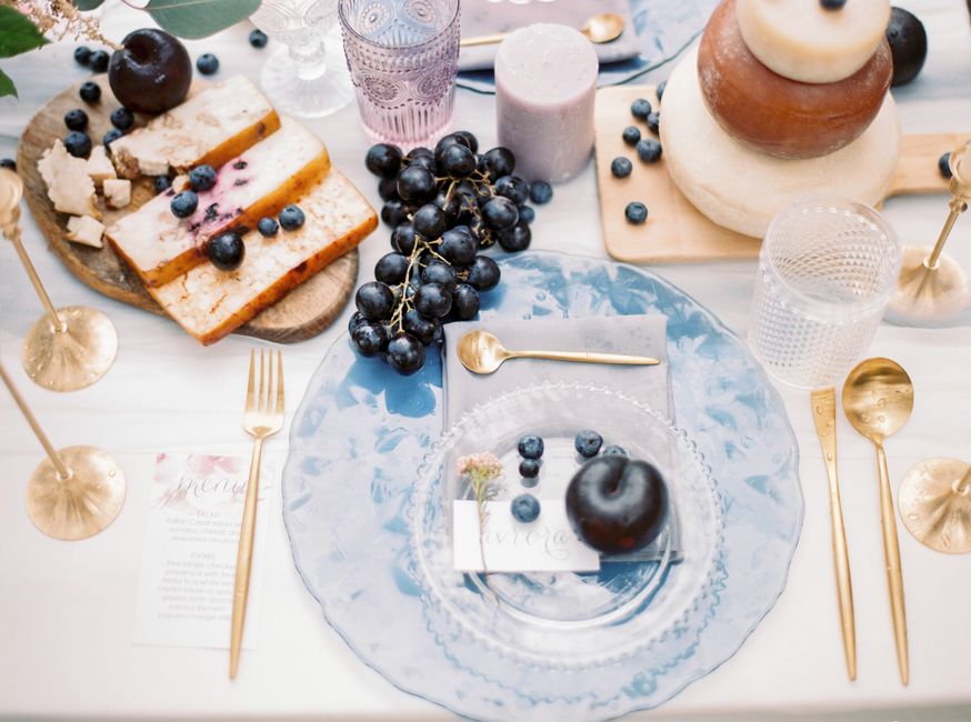 Elegant wedding table setting featuring fruits, layered cake, and gold flatware, creating a chic and festive atmosphere.