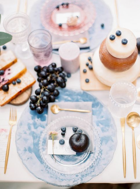 A sophisticated table arrangement featuring a cake, blueberries, and elegant tableware.
