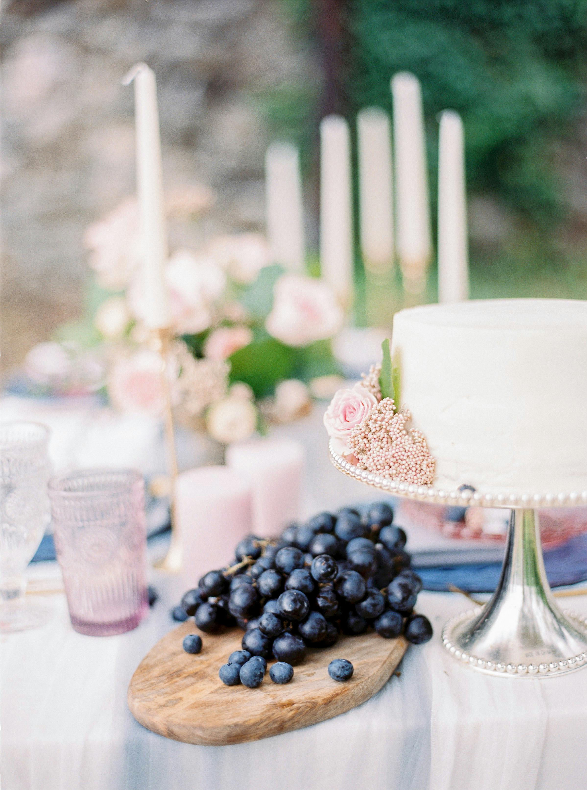Stylish cake and grapes on a decorated table with pink accents, ideal for wedding celebrations.