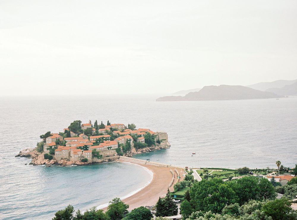 Plaja arcuită cu pietriș rozaliu de lângă insula Sveti Stefan, cu apă limpede