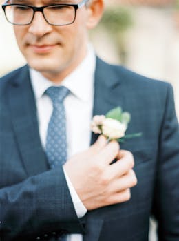 Close-up of a groom adjusting his boutonniere, showcasing elegance and style on a special day.