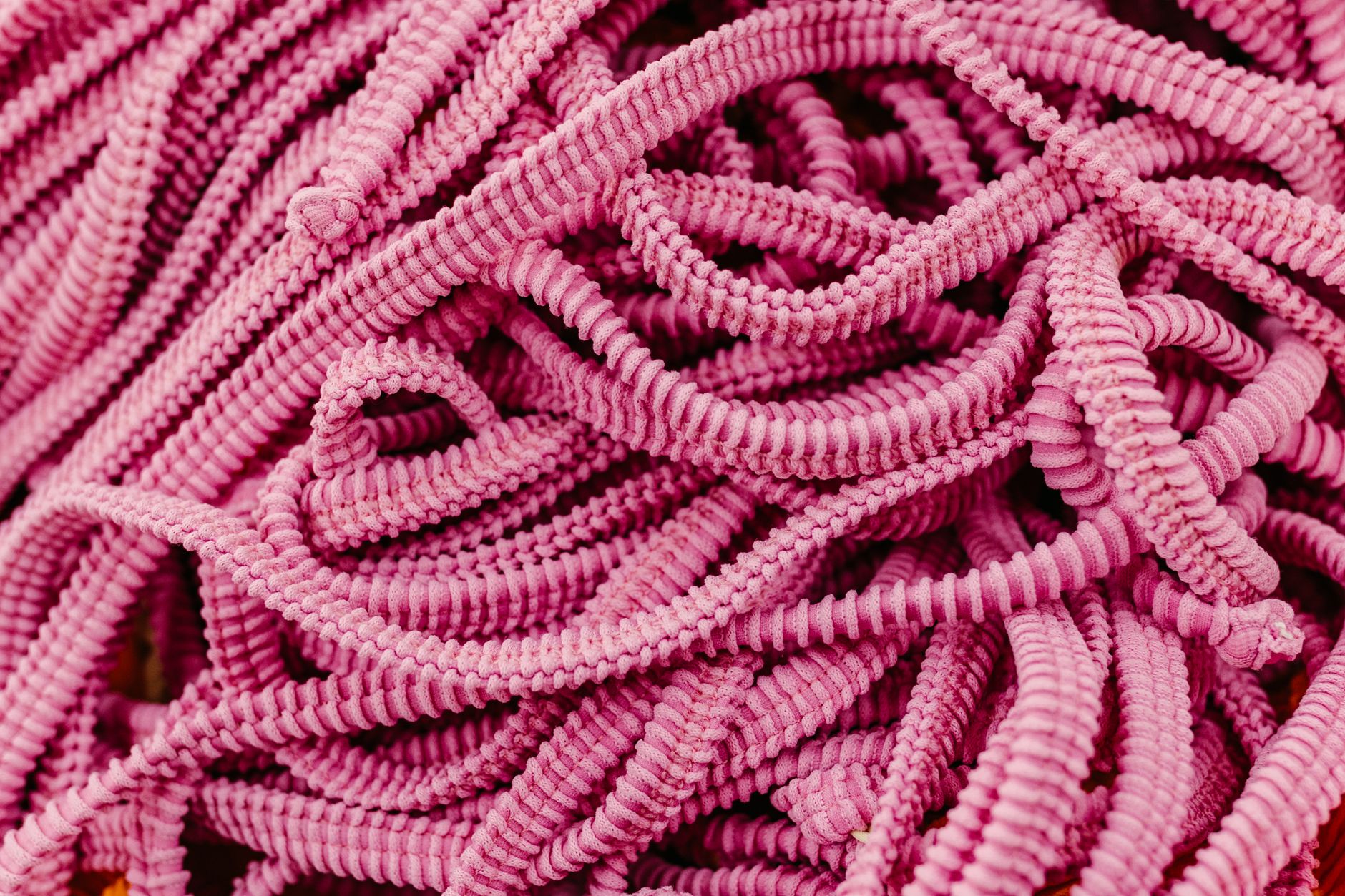 A detailed close-up of twisted pink elastic cords forming intricate patterns.