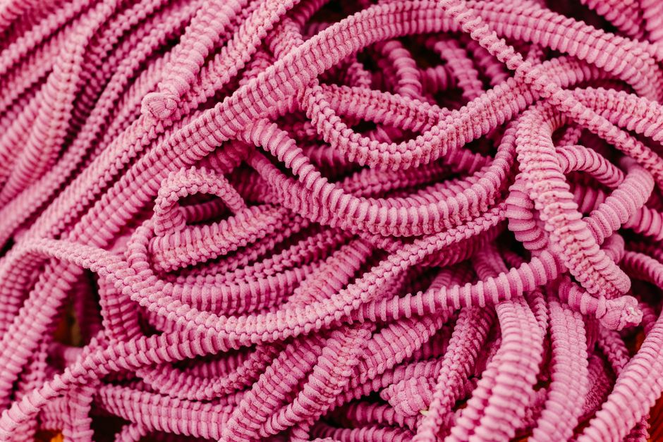 A detailed close-up of twisted pink elastic cords forming intricate patterns.