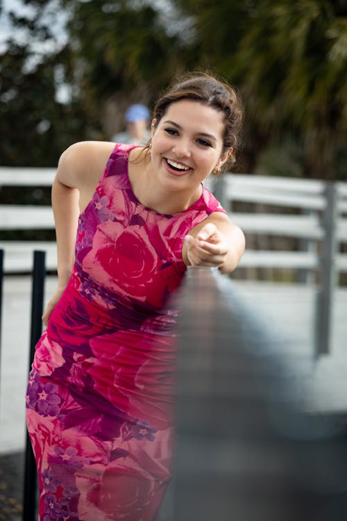 A Woman in Pink Dress Leaning on the Metal Railing 