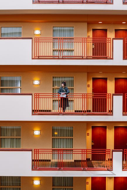 A woman stands on a balcony in a modern apartment building, showcasing urban living.