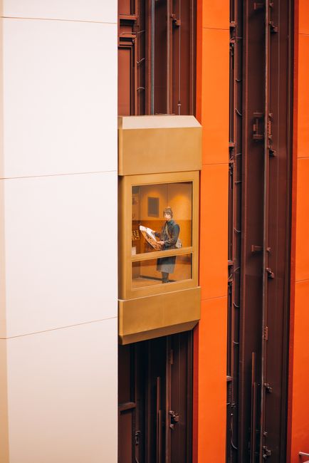 A woman travels in a glass elevator within a modern skyscraper, showcasing urban architecture.