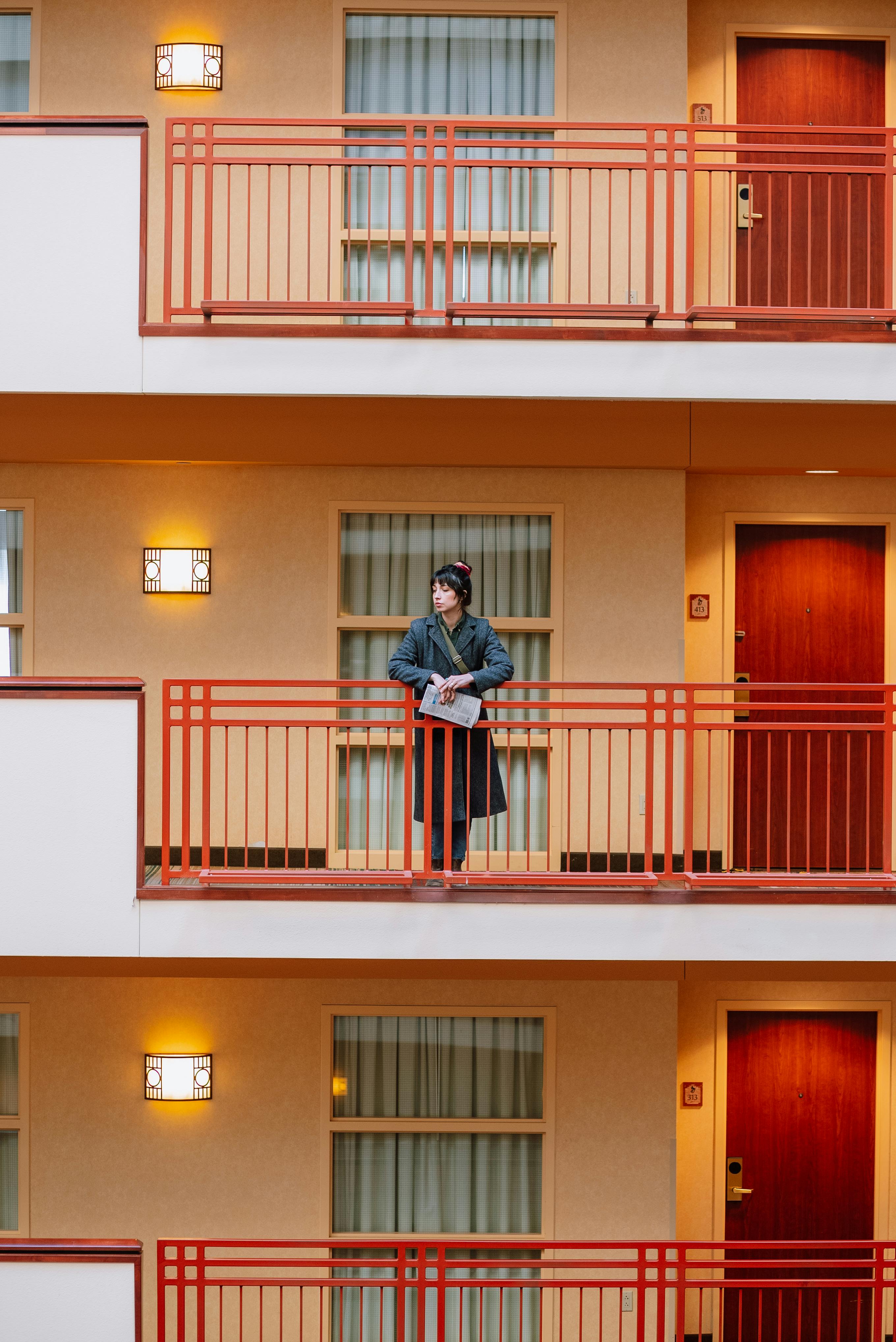 A woman stands on a hotel balcony, showcasing contemporary architecture and design.