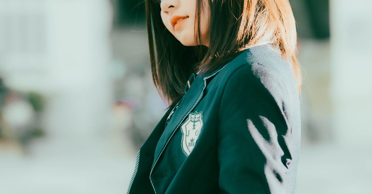 A Girl in a Uniform Leaning on a Railing · Free Stock Photo