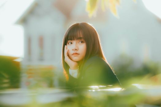 Young woman in outdoor setting with thoughtful expression at sunset in nature.