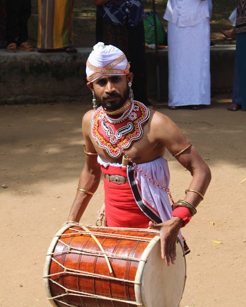 Man in Traditional Costume Playing on Drum