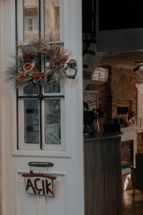 Free A rustic white door with a handmade wreath and 'open' sign, inviting interior view. Stock Photo