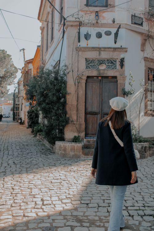 Free A woman strolls down a picturesque cobblestone street in an old town, embracing a serene urban atmosphere. Stock Photo