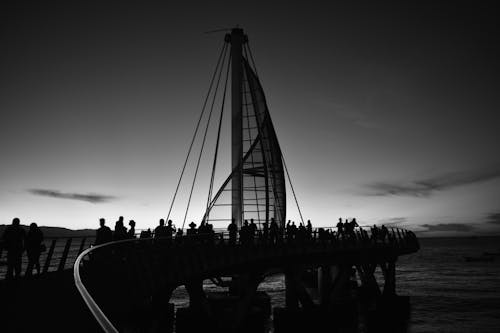 Black and White Photo of People Standing on a Bridge 