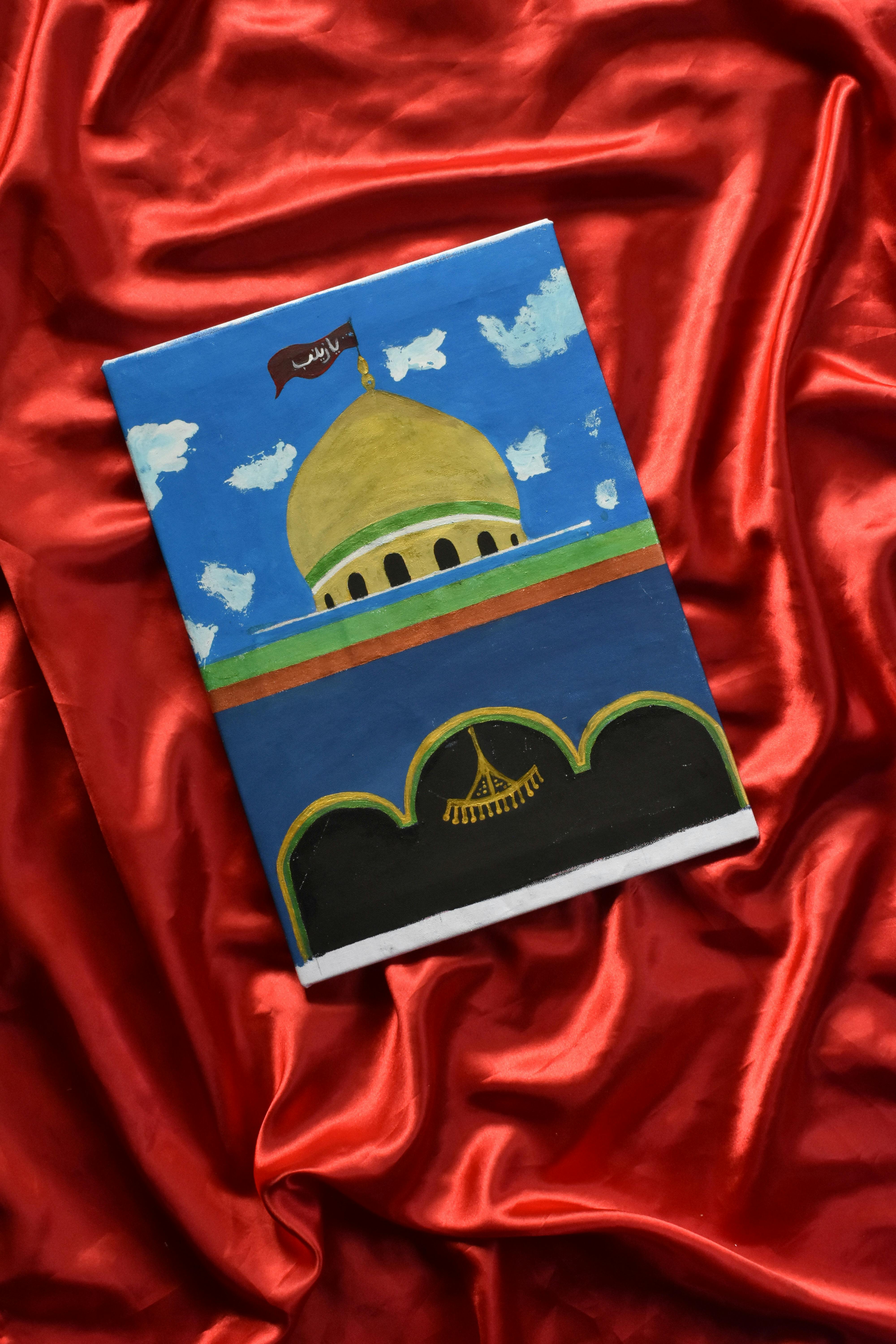An oil painting of a mosque dome with a vibrant sky, set on red fabric.
