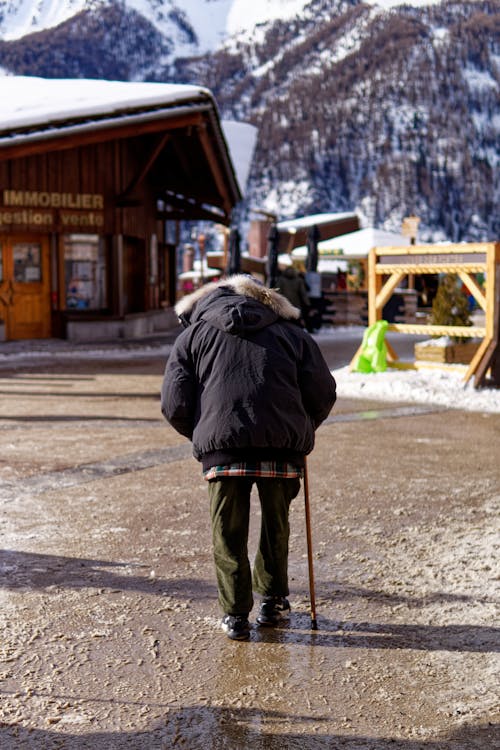 A Person in Blue Jacket Walking with Walking Stick