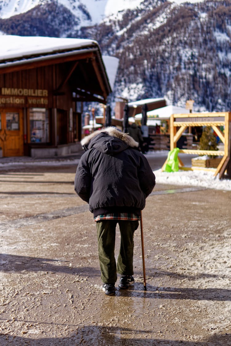 A Person In Blue Jacket Walking With Walking Stick