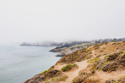 Free Hills Beside Body of Water Covered With Fog Stock Photo