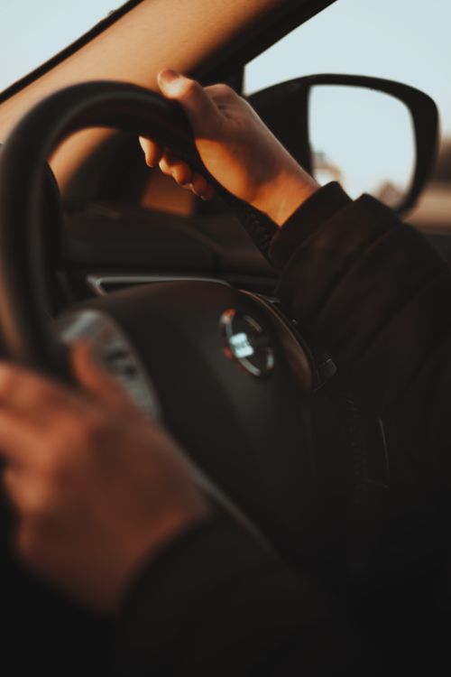 Free Close-up photo of hands gripping a steering wheel while driving, with a warm and neutral tone. Stock Photo