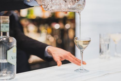 Free Close-up of bartender pouring gin into a glass for a martini, showcasing cocktail preparation at a Paris bar. Stock Photo