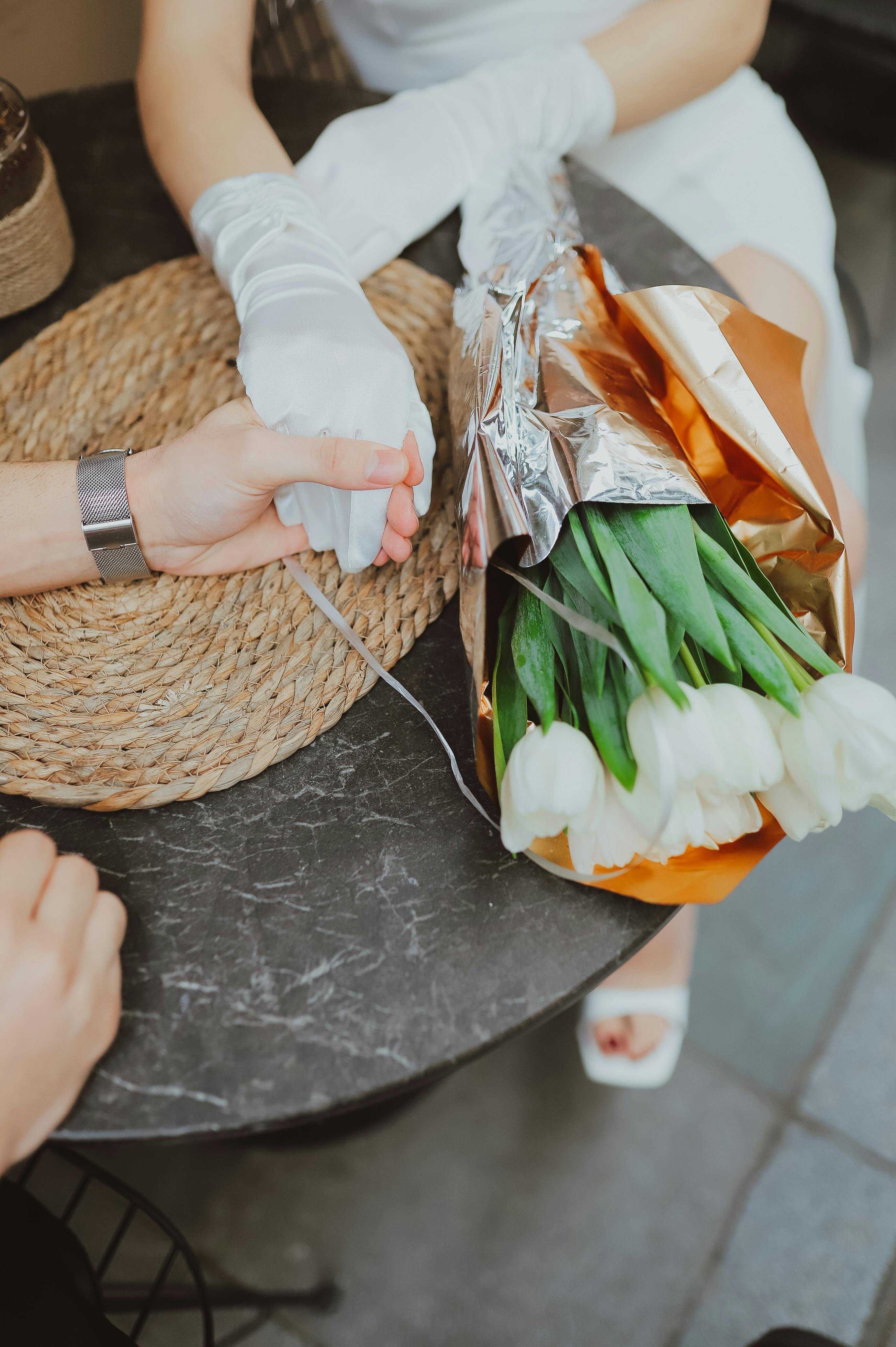 Romantic scene of a couple holding hands with white tulips on a café table in İstanbul.