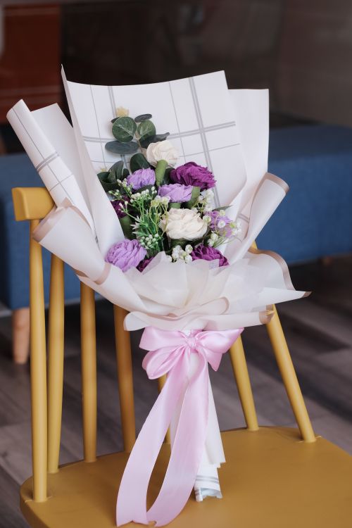 Free A stunning floral bouquet placed elegantly on a yellow chair indoors. Stock Photo