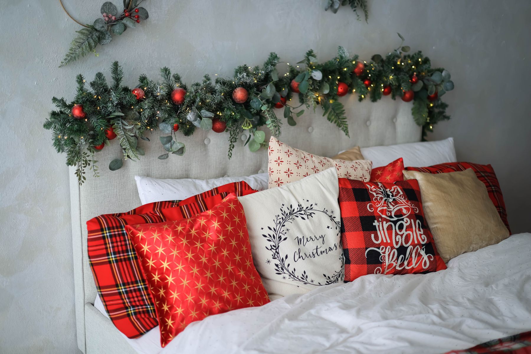 Bed styled with plaid Christmas pillows greenery and small festive details
