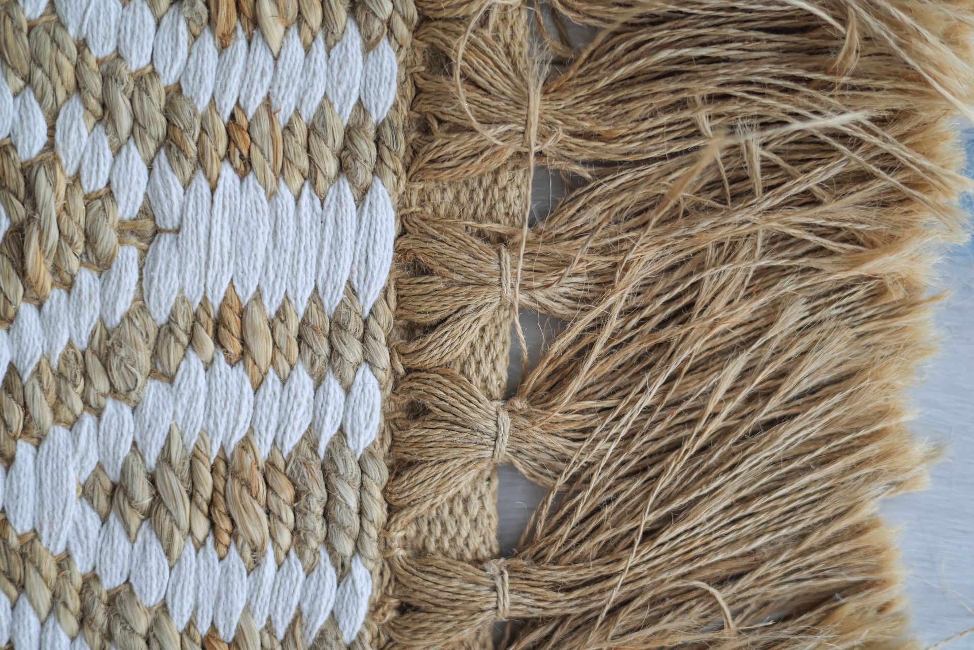 Detailed view of jute and fiber weaving with tassel fringe, showcasing intricate texture.