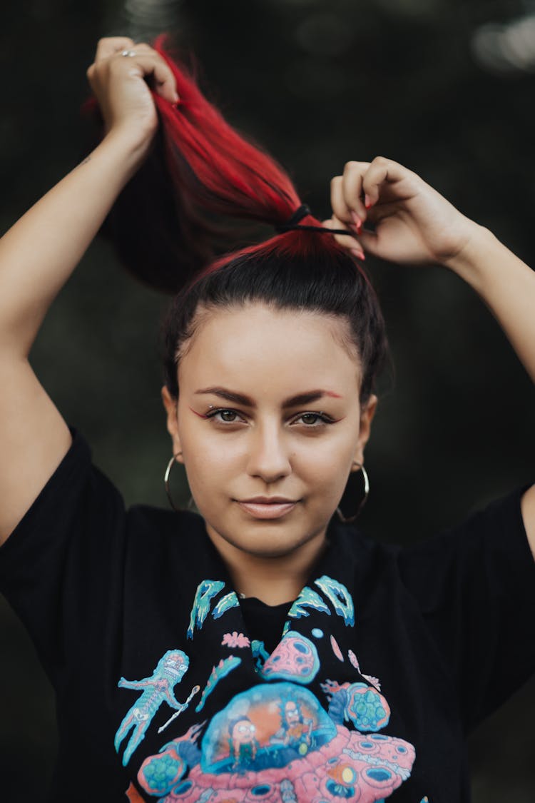 Photo Of A Girl Tying Her Hair In A Ponytail 